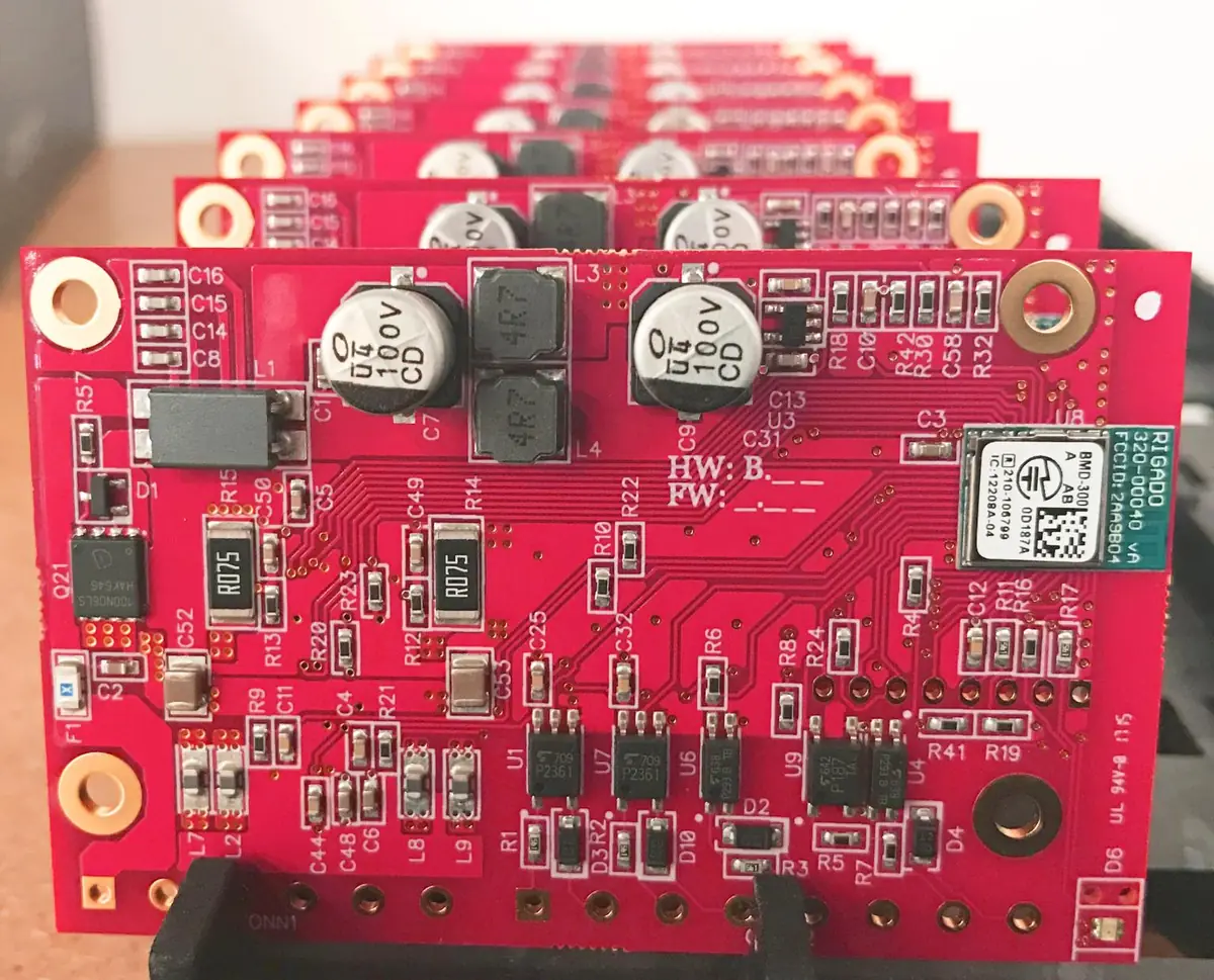 Assembled red PCBAs with electrolytic capacitors, power inductors and a wireless module, stacked in a board rack