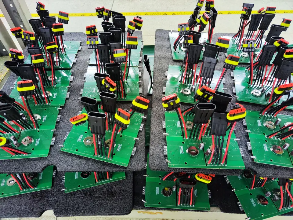 Assembled boards with sealed automotive-style connectors and red-black leads soldered on, held in black foam trays