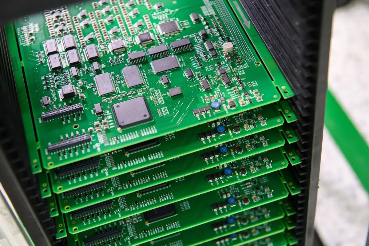 Stack of assembled high-density PCBAs with QFP, TSOP and SOIC packages in an SMT magazine rack