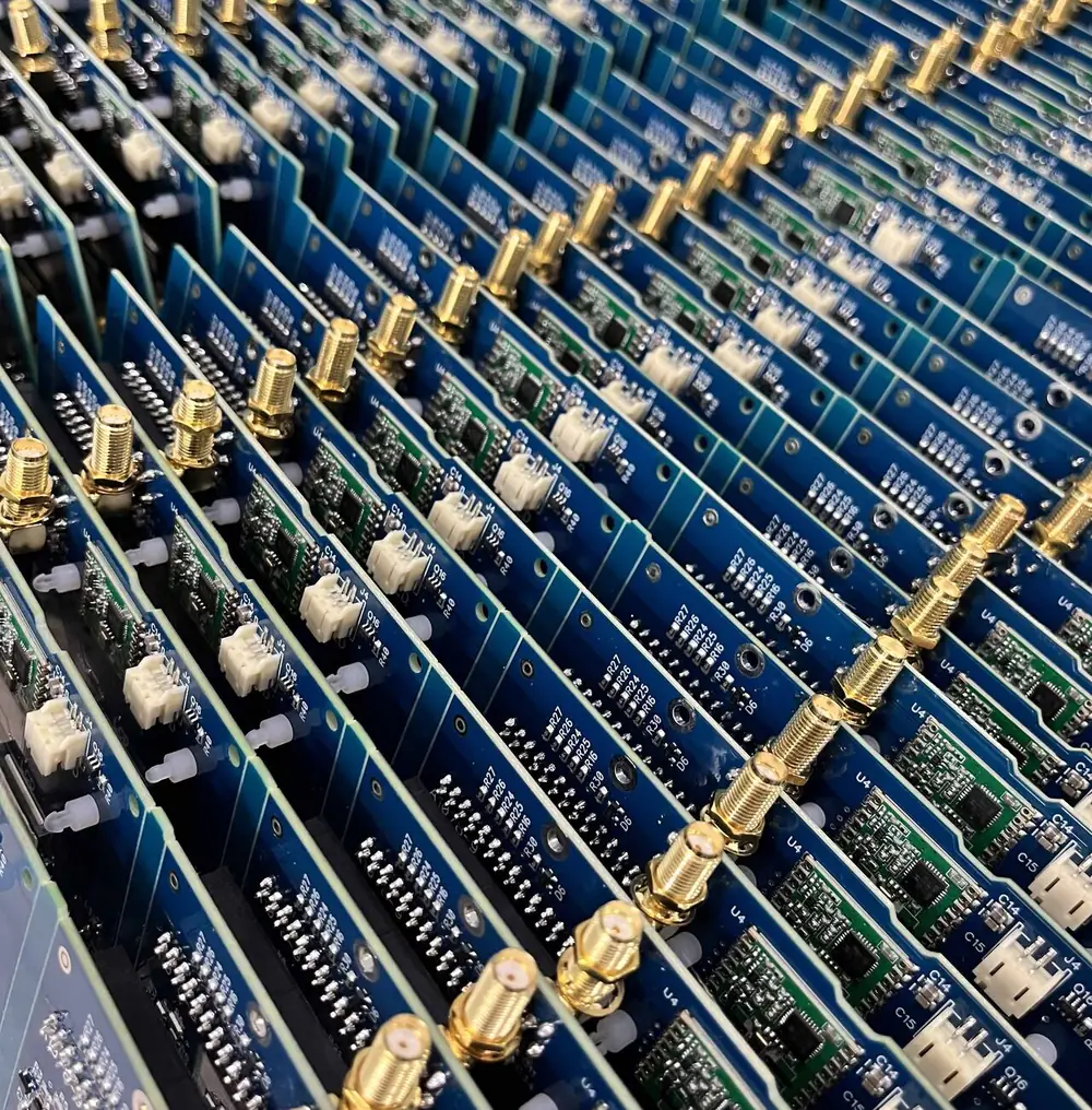 Rows of assembled blue RF boards with gold-plated SMA connectors and white 2-pin headers